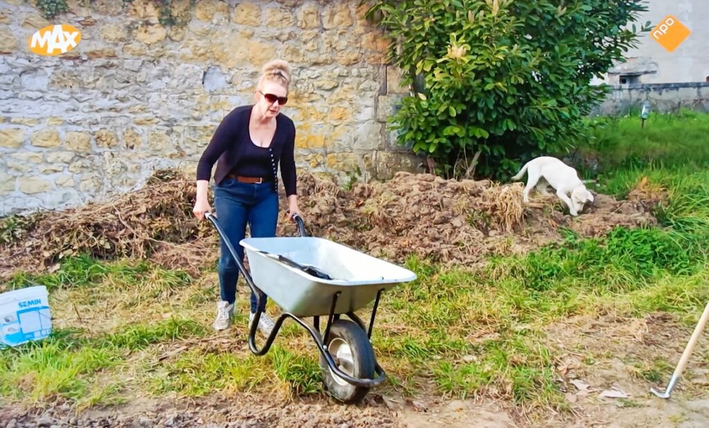 Kasteelvrouwe Emmy loopt achter kruiwagen in moestuin