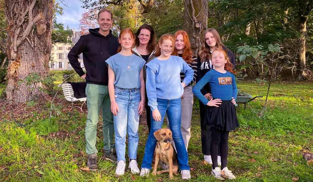 Familie Jansen, bestaande uit vader Ray, moeder Margriet en hun 5 dochters poseren buiten in het gras in Frankrijk voor het Avrotros programma Ik Vertrek.