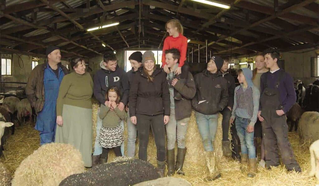 Familie van Dool poseert in de schapenstal voor het RTL5 tv-programma Bij ons op de Boerderij.