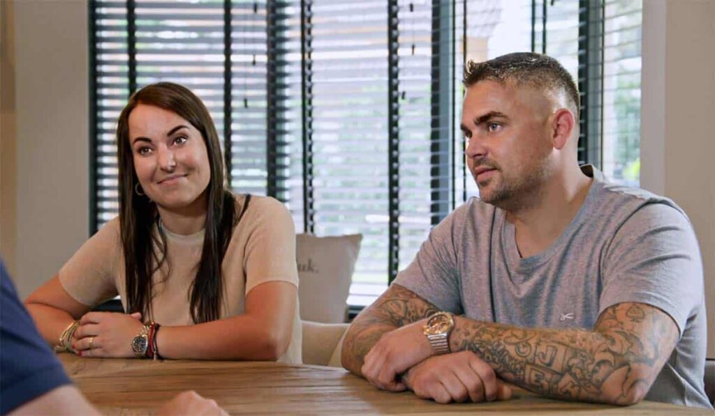 De Moeite Waard deelnemers Esmee en Marcel zitten aan tafel in hun villa in Almere.