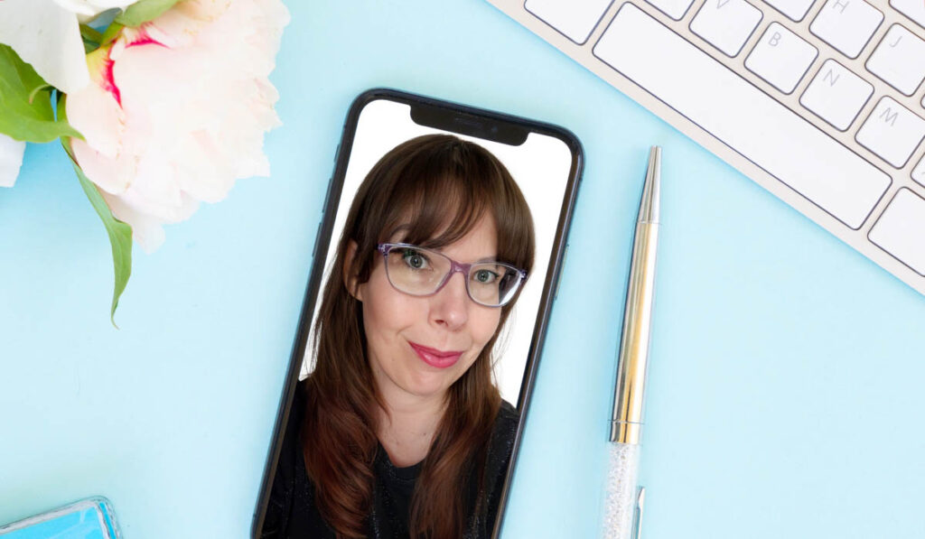 Blauwe achtergrond, keyboard, pen, bloem en telefoon met selfie van vrouw.